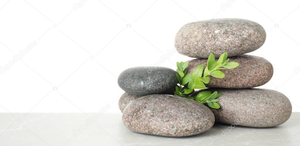 Stack of spa stones and leaves on table against white background. Space for text