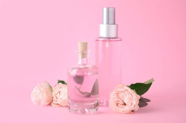 Pembe arka plan üzerinde uçucu yağ ve gül şişeleri