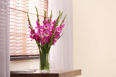 Odada ahşap masada güzel pembe gladiolus çiçek ile Vazo, metin için alan
