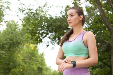 Genç kadın parkta eğitim den sonra akıllı saat ile nabız kontrol. Metin için alan