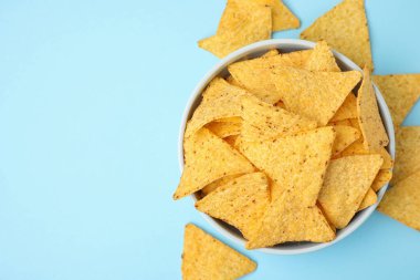 Açık mavi arka plan üzerinde lezzetli Meksika nachos cips ile Bowl, düz yatıyordu. Metin için alan