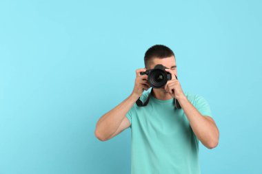 Genç profesyonel fotoğrafçı açık mavi arka plan üzerinde fotoğraf çekiyor. Metin için alan