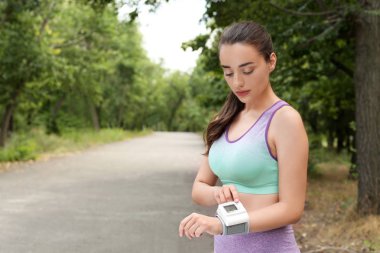 Genç kadın parkta eğitim den sonra tıbbi cihaz ile nabız kontrol. Metin için alan