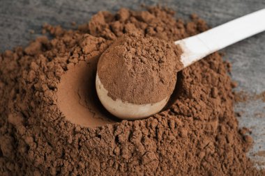 Çikolata protein tozu yığını ve gri masaya kepçe, closeup