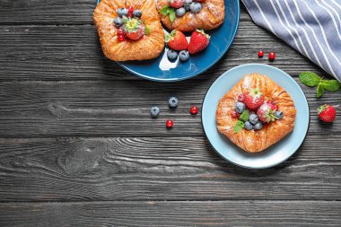 Koyu ahşap arka plan üzerinde tatlı çilek ile taze lezzetli puf böreği, düz yatıyordu. Metin için alan