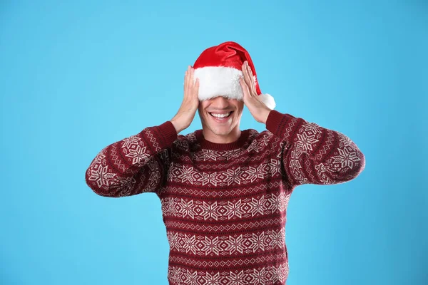 Ung man i julen tröja och Santa hatt på ljusblå bakgrund — Stockfoto