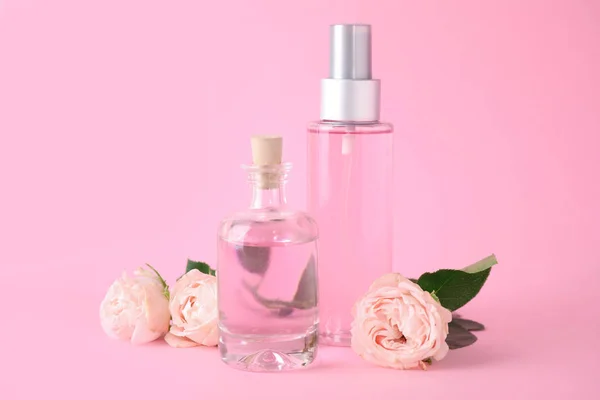 Flaschen ätherisches Öl und Rosen auf rosa Hintergrund — Stockfoto
