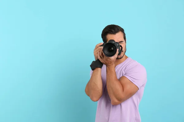 Joven fotógrafo profesional tomando fotos sobre fondo azul claro. Espacio para texto — Foto de Stock