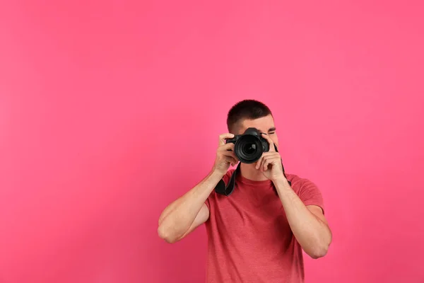 Joven fotógrafo profesional tomando fotos sobre fondo rosa. Espacio para texto —  Fotos de Stock