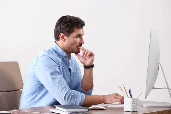 Beau jeune homme travaillant avec ordinateur à la table dans le bureau — Photo