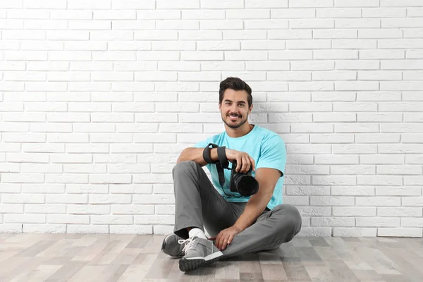 Tuğla duvara yakın profesyonel kamera ile genç fotoğrafçı. Metin için alan