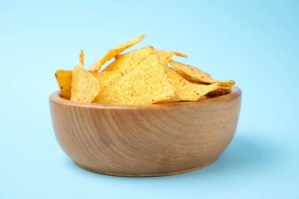 Wooden bowl with tasty Mexican nachos chips on light blue background — Stock Photo, Image