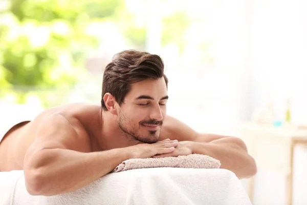 Schöner junger Mann entspannt auf Massagetisch im Wellness-Salon, Platz für Text — Stockfoto