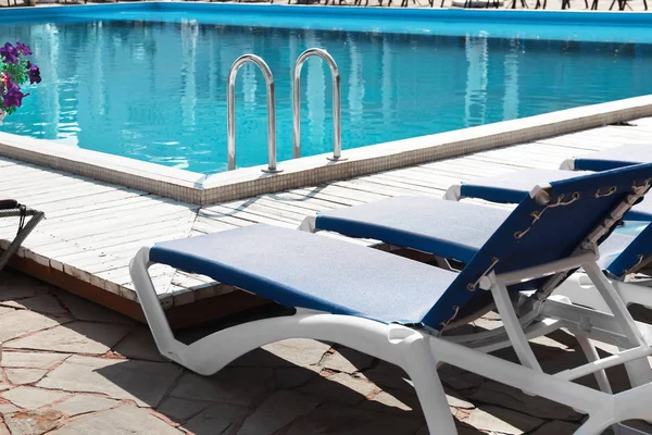 Komfortable Liegestühle am sauberen Pool an sonnigen Tagen — Stockfoto