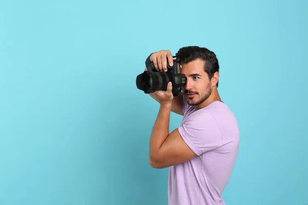 Junger professioneller Fotograf beim Fotografieren auf hellblauem Hintergrund. Raum für Text — Stockfoto