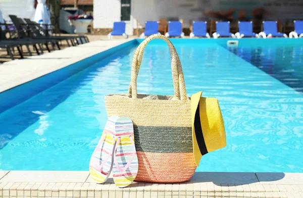 Bolsa con accesorios de playa cerca de la piscina en un día soleado —  Fotos de Stock