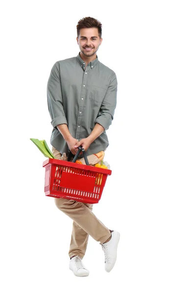 Νέος άνθρωπος με καλάθι αγορών γεμάτο προϊόντα που απομονώνονται σε λευκό — Φωτογραφία Αρχείου