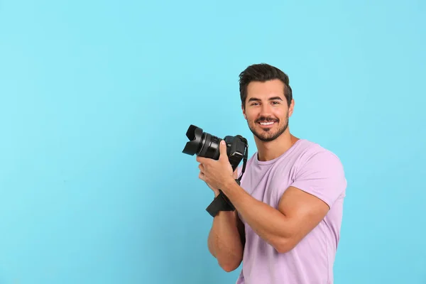 Jovem fotógrafo com câmera profissional em fundo azul claro. Espaço para texto — Fotografia de Stock