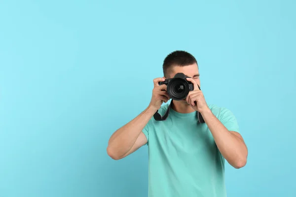 年轻的专业摄影师在浅蓝色背景上拍照。文本空间 — 图库照片