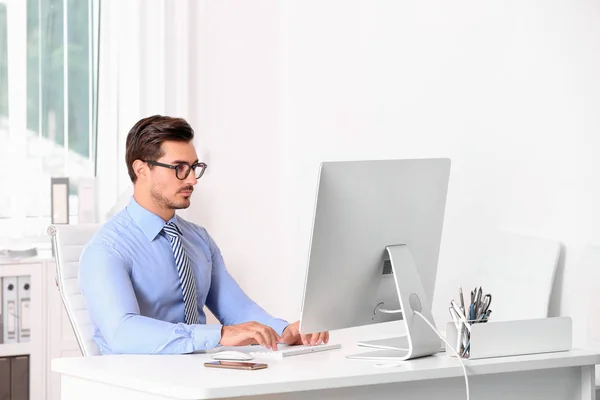 Schöner junger Mann arbeitet mit Computer am Tisch im Büro — Stockfoto