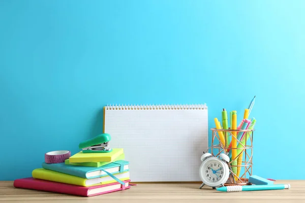 Diferentes artigos de papelaria escolar e caderno em branco na mesa perto da parede azul clara. Espaço para texto — Fotografia de Stock