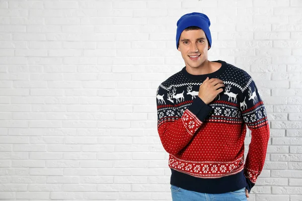 Retrato de jovem em camisola de Natal e chapéu perto da parede de tijolo branco. Espaço para texto — Fotografia de Stock