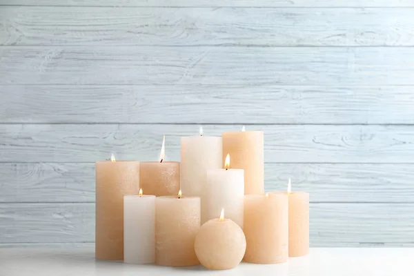 Conjunto de velas em chamas na mesa contra fundo de madeira leve — Fotografia de Stock