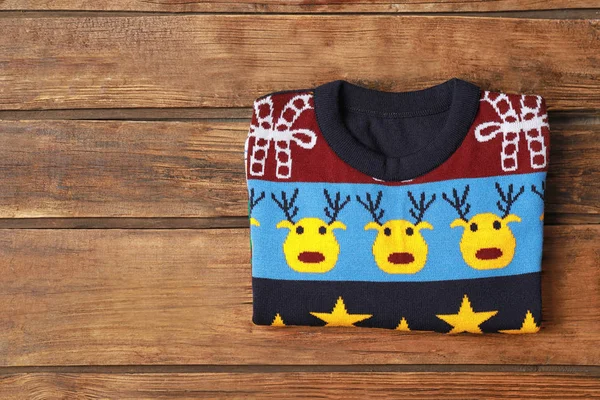 Warm folded Christmas sweater on wooden table, top view. Space for text — Stock Photo, Image