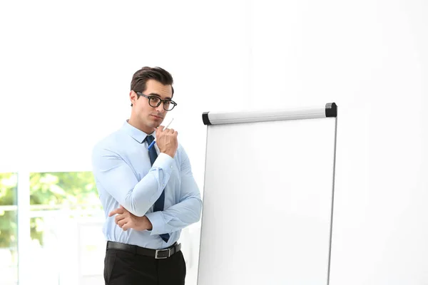 Professional business trainer near flip chart in office