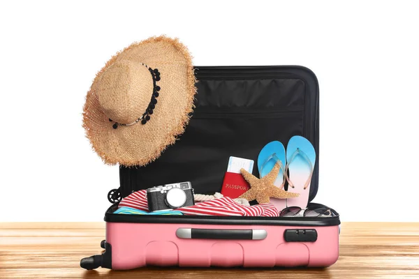Nyílt rózsaszín bőrönde különböző strand tárgyak fa asztal, fehér háttér — Stock Fotó
