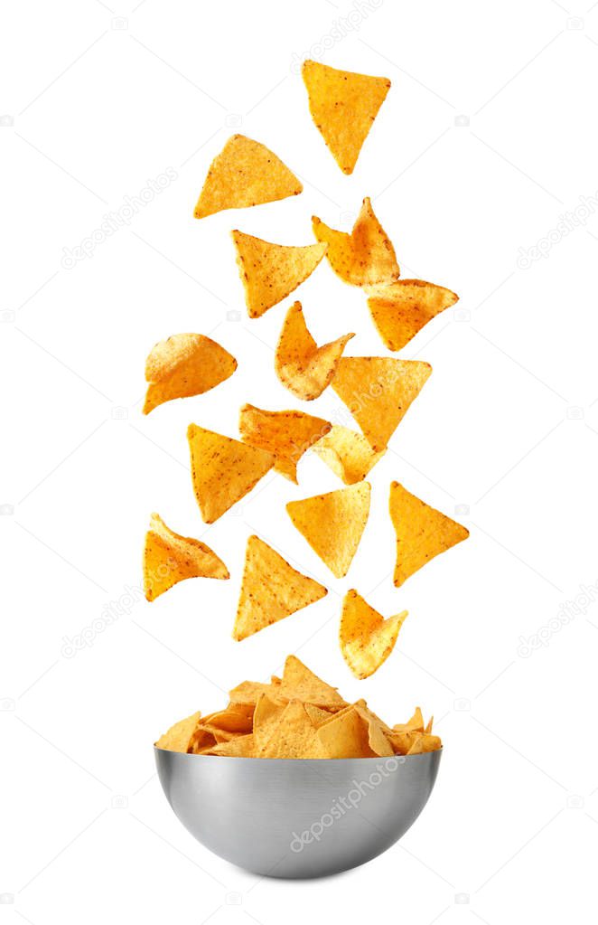 Delicious Mexican nachos chips falling into bowl on white background