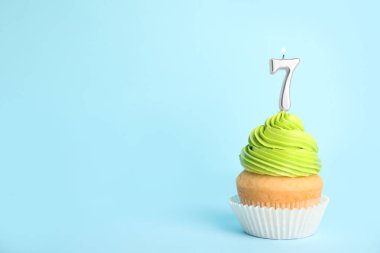 Mavi arka plan üzerinde yedi numaralı mum ile Doğum günü cupcake, metin için alan