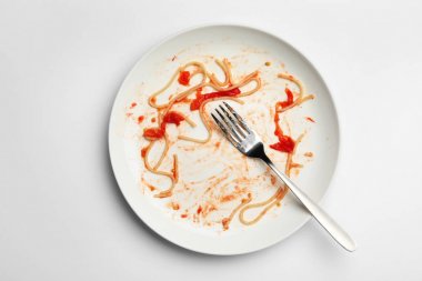 Beyaz arka planda yemek artıkları ve çatal ile kirli plaka, üst görünümü