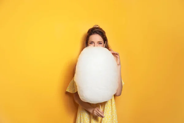 Sarı arka planda lezzetli pamuk şeker ile genç kadın — Stok fotoğraf
