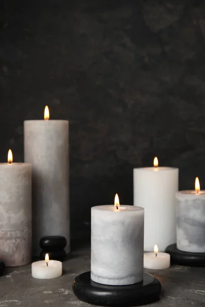 Brandende kaarsen en Black Spa Stones op grijze tafel, ruimte voor tekst — Stockfoto
