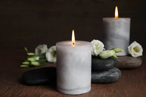 Queimando velas, pedras de spa e flores na mesa de madeira — Fotografia de Stock