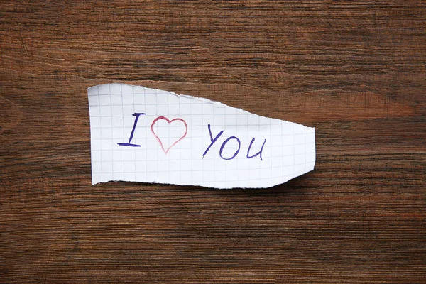 Arkusz papieru ze słowami kocham Cię na drewnianym stole, widok z góry — Zdjęcie stockowe