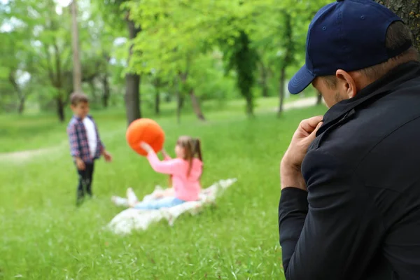Podezřelý dospělý muž špehuje děti v parku. Dítě v nebezpečí — Stock fotografie