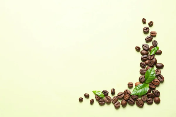 Fresh green coffee leaves and beans on light green background, flat lay. Space for text