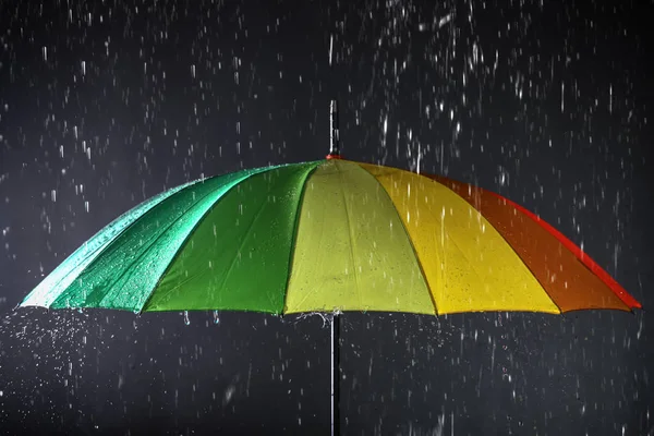 Parapluie lumineux sous la pluie sur fond sombre — Photo