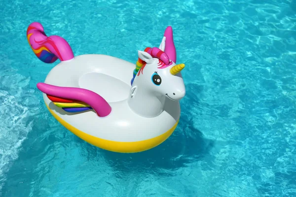 Divertente anello gonfiabile unicorno galleggiante in piscina nella giornata di sole. Spazio per testo — Foto Stock