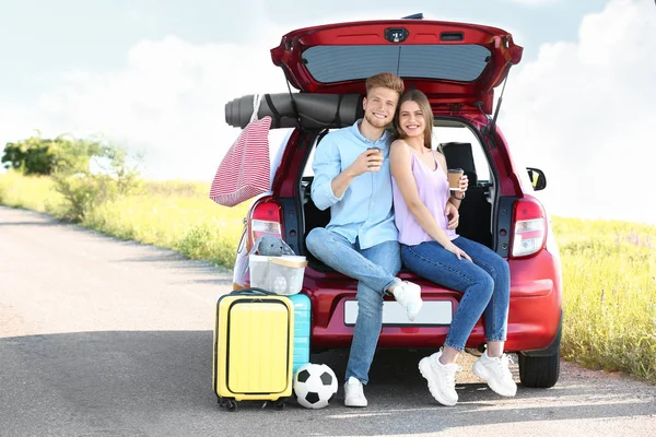 Jovem casal com bagagem perto do porta-malas do carro ao ar livre — Fotografia de Stock