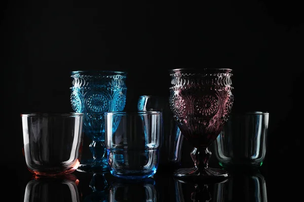 Ensemble de différents verres vides colorés sur fond noir — Photo