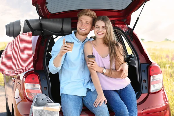 Young couple with luggage near car trunk outdoors