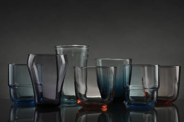 Uppsättning av olika färgglada tomma glasögon på bordet mot grå bakgrund — Stockfoto
