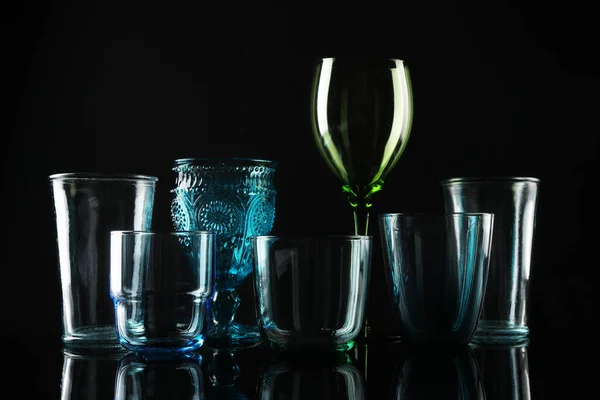 Ensemble de différents verres vides colorés sur fond noir — Photo