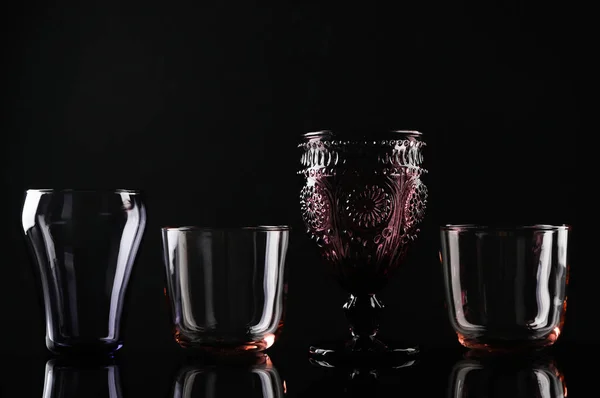 Set aus verschiedenen bunten leeren Gläsern auf schwarzem Hintergrund — Stockfoto