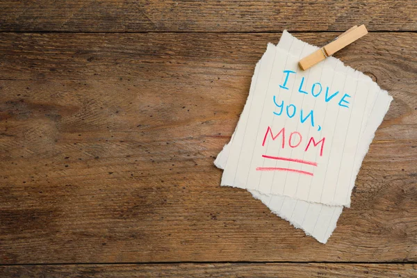 Paper sheets with words I LOVE YOU MOM and peg on wooden table, top view. Space for text — Stock Photo, Image