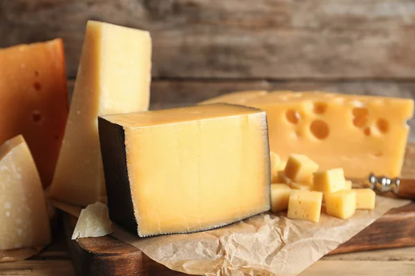 Různé druhy lahodného sýra na stole proti dřevěnému pozadí — Stock fotografie