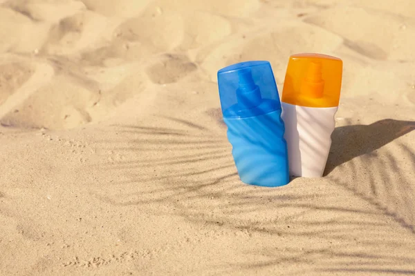 Butelki z filtrem przeciwsłonecznym w piasku plażowego. Miejsce na tekst — Zdjęcie stockowe